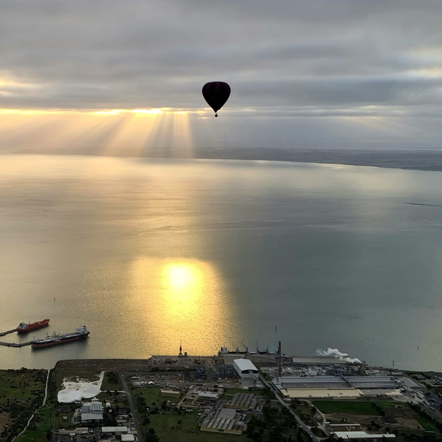 Hot air balloon at sunrise over The Great Ocean Flight Geelong and Bellarine, calm waters, ships below, breakfast included.