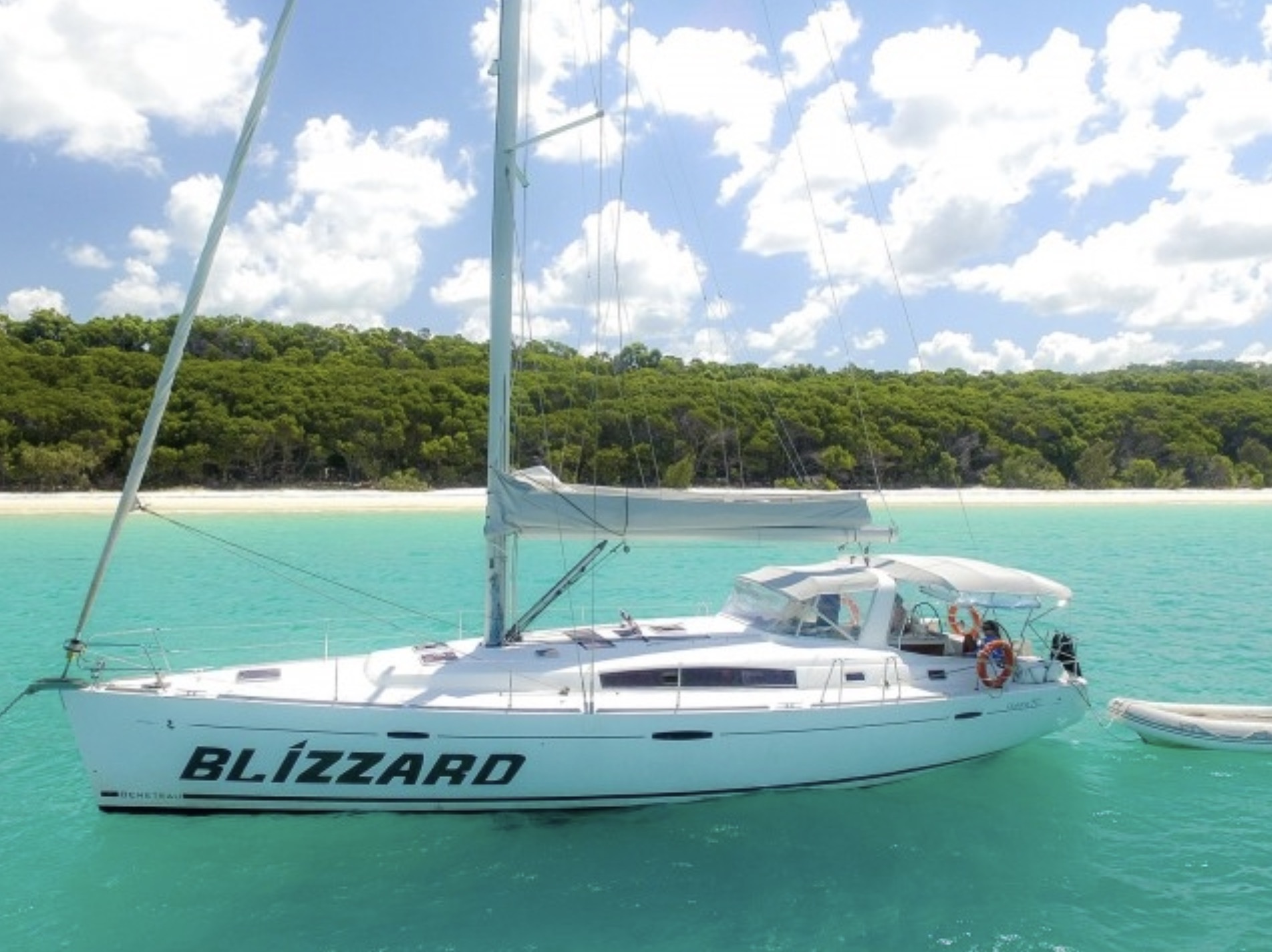 A sleek white sailboat, BLIZZARD, glides on vibrant turquoise Whitsunday waters—ideal for a 3-day, 2-night sailing adventure.