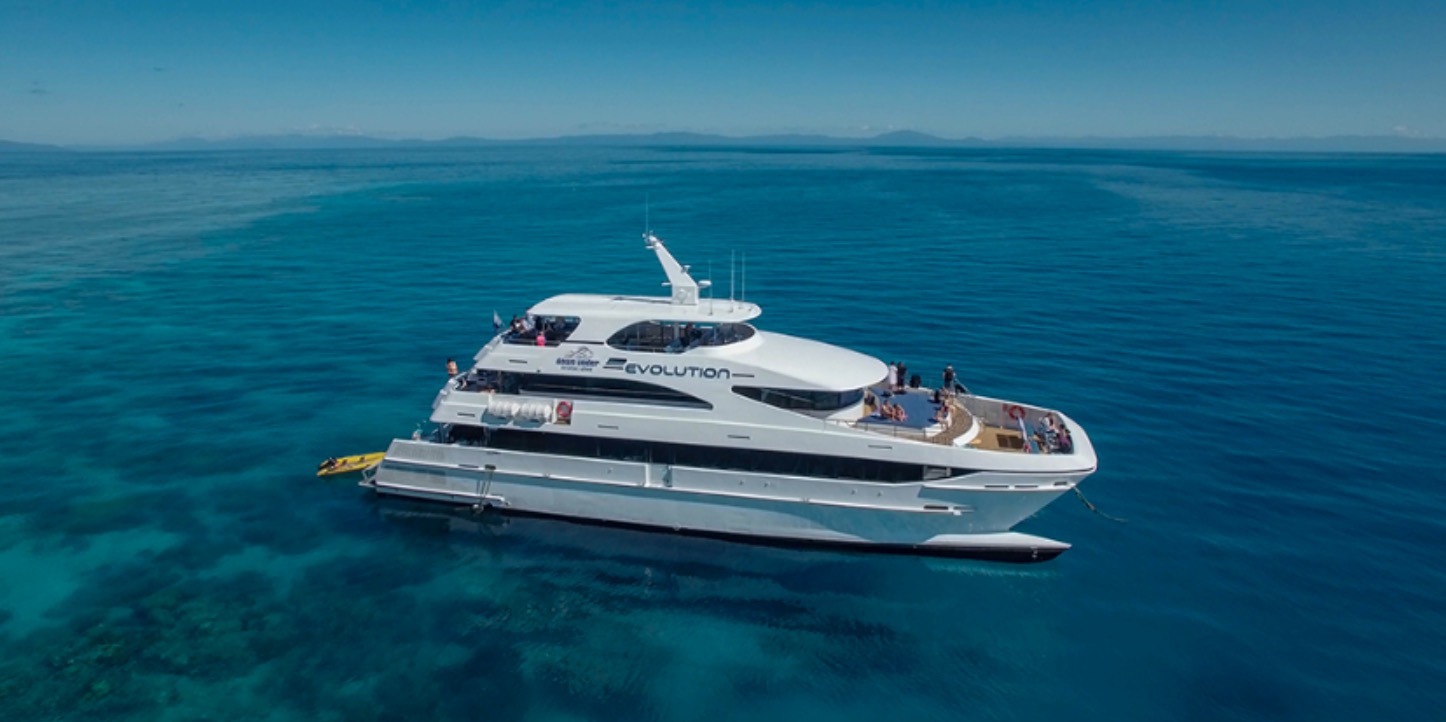 Experience the Full Day Great Barrier Reef Cruise aboard the Evolution yacht, gliding on crystal-clear ocean under a radiant blue sky.