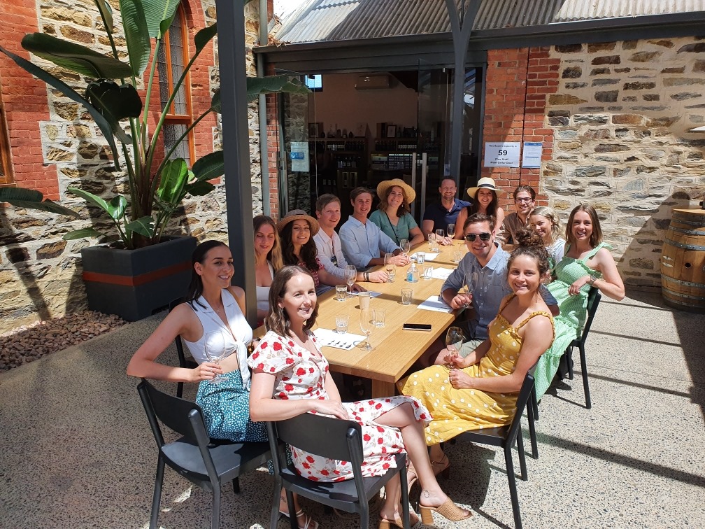 Friends savour wine and cocktails at a bright outdoor café, unwinding post 1 Day Wine Tasting Coast Afternoon Tour by the seaside.