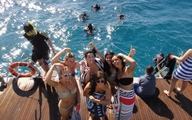 Smiling friends in swimwear enjoy a sun-filled boat ride on The Great Escape Australia 28 Day Semi-Guided tour adventure.