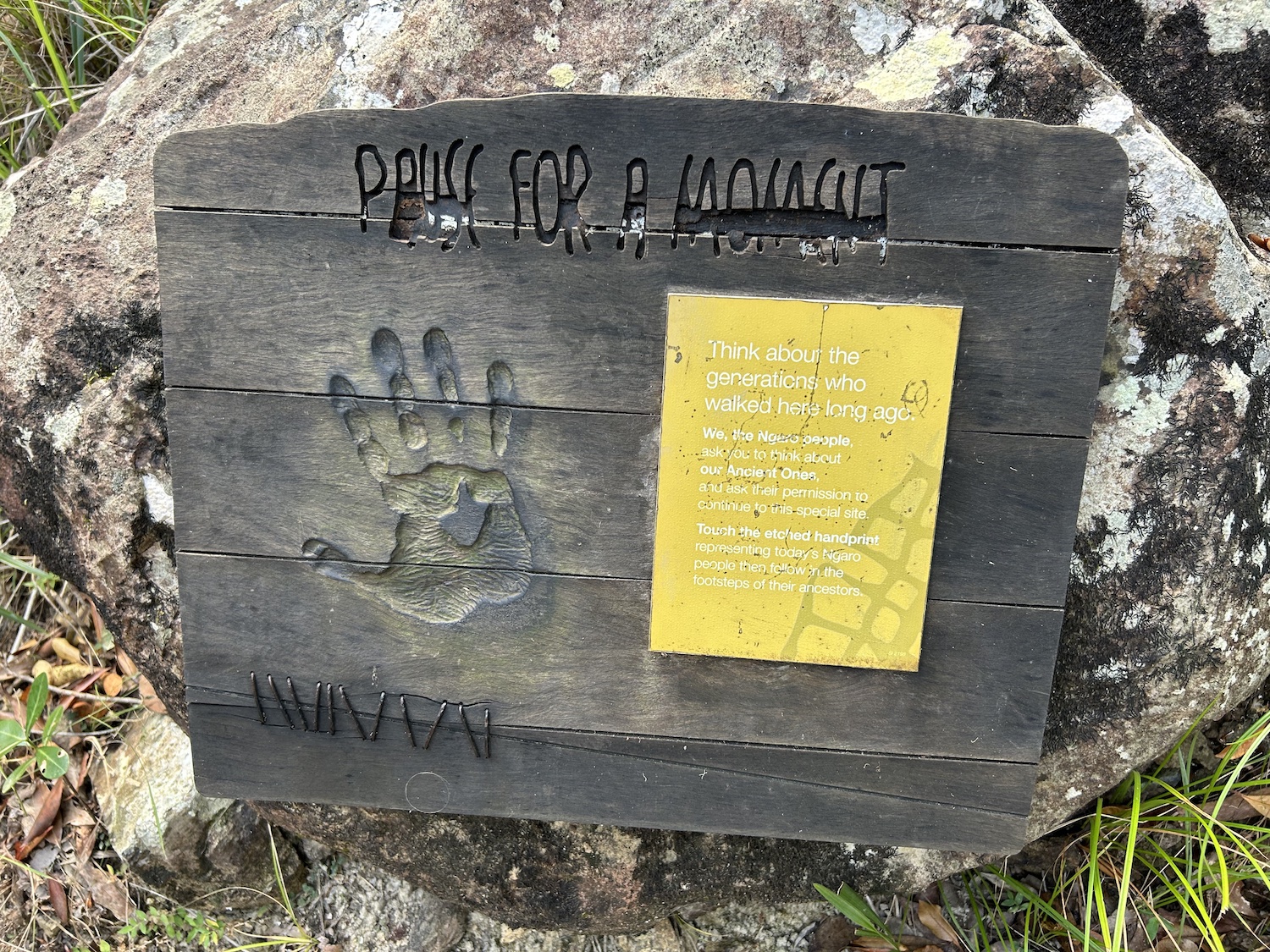 Hook Island cultural legacy sign: wooden board with handprint, engraved lettering, yellow plaque highlighting island heritage.