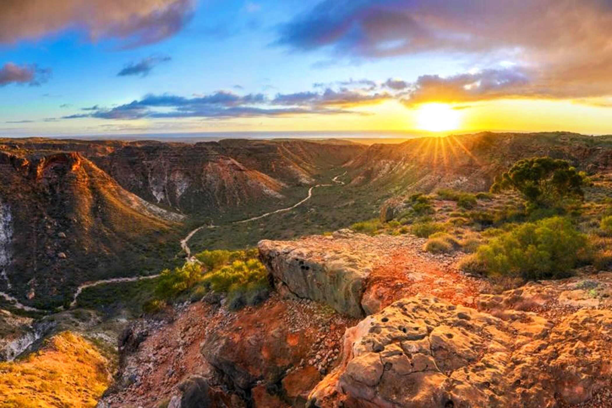 Breathtaking sunrise illuminates a dramatic canyon on the 8-Day Perth to Exmouth Comfort Tour, showcasing iconic coast and cliffs.