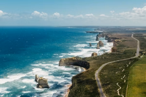 Birds eye view of great ocean road. the left has the bright blue ocean and the right is the rugged hills with the road on it